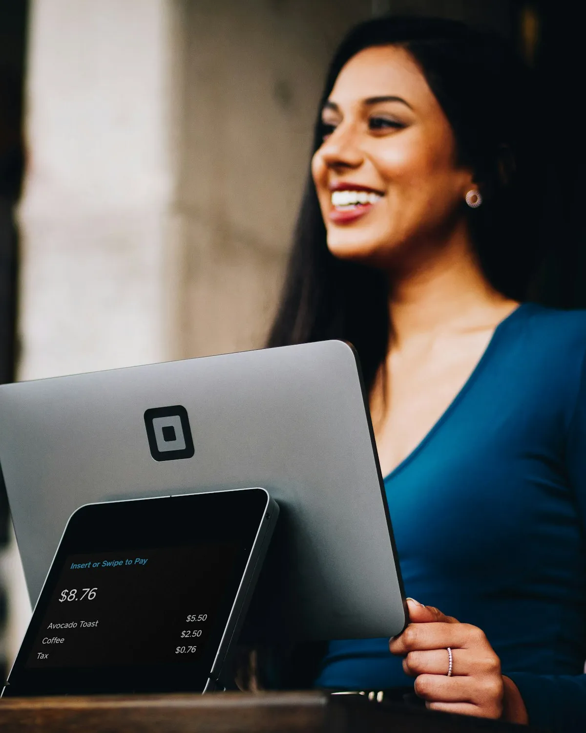 Dueña de negocio sonriente cobrando a un cliente en una terminal de punto de venta