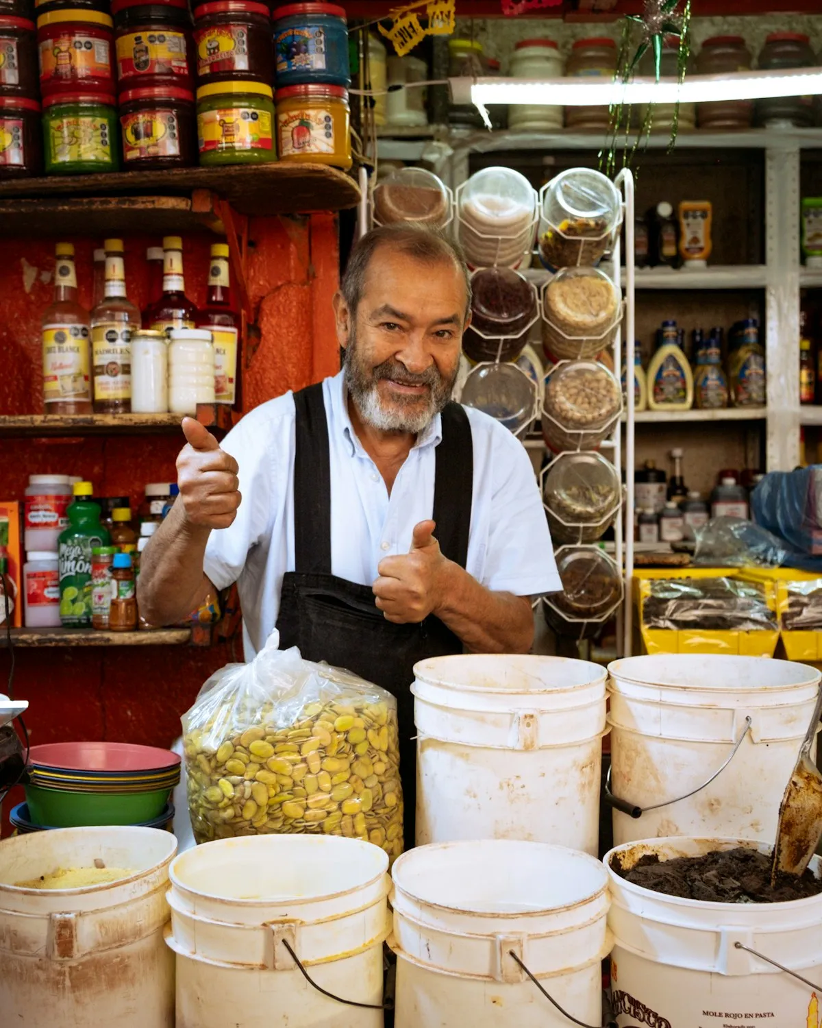 Comerciante sonriente con el pulgar arriba detrás del mostrador de su tienda